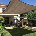 شبك تظليل بنّي مشدود فوق فناء منزل مع حلقات تثبيت على الحواف | Brown shade net tensioned over a house patio with grommets along the edges
