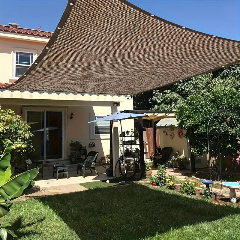 شبك تظليل بنّي مشدود فوق فناء منزل مع حلقات تثبيت على الحواف | Brown shade net tensioned over a house patio with grommets along the edges