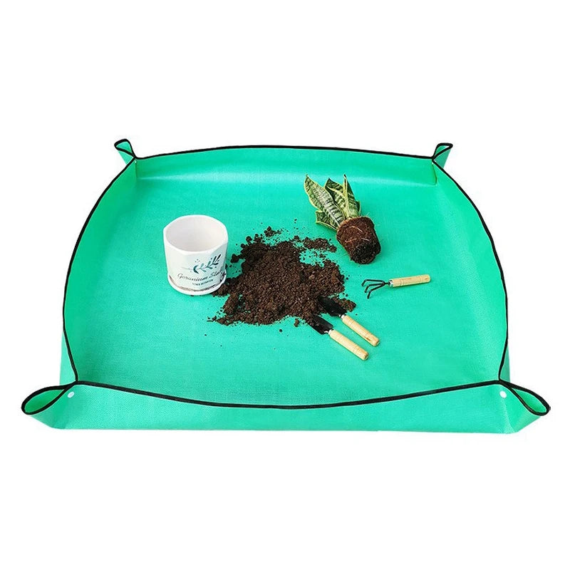 حصيرة إعادة الزراعة الخضراء مفرودة مع تربة وأدوات بستنة | The green repotting mat opened out with soil and gardening tools