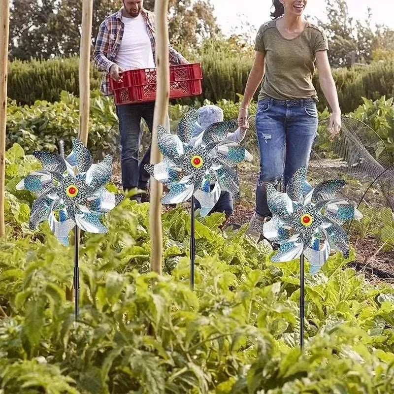 ثلاثة دوّارات عاكسة مغروزة بين محاصيل خضار في حقل | Three reflective windmills staked among vegetable crops in a field