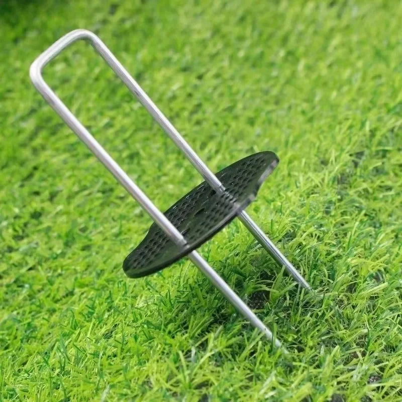 وتد تثبيت مجلفن على شكل حرف U مع قرص تثبيت مثقّب مركّب عليه على العشب | Galvanised U-shaped ground staple with a perforated retaining pad fitted, shown on turf